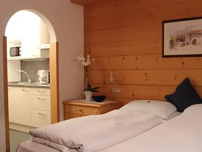 a bedroom with two beds and a kitchen at Residence Lastei in Ortisei