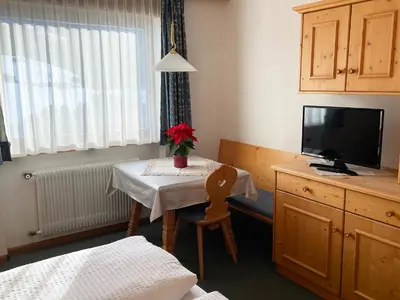 a room with a table with a tv and a table with a chair at Residence Lastei in Ortisei