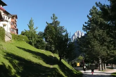 a group of people walking down a street with a mountain at Apartment Cesa Collina Family Retreat in Ortisei