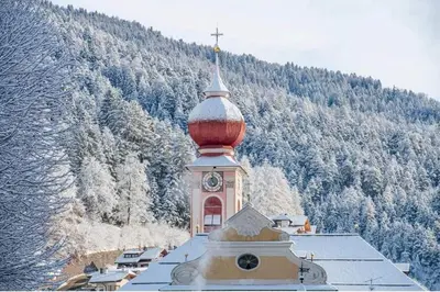 a clock tower on top of a building with a mountain at Apartment Cesa Collina Family Retreat in Ortisei