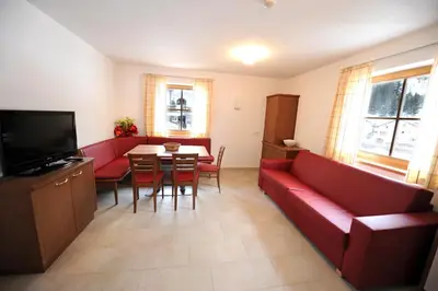 a living room with a red couch and a table at Apartments Rusctlea in Selva di Val Gardena