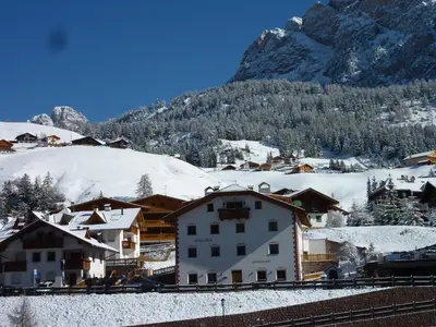 a snow covered village with a mountain in the background at Apartments Rusctlea in Selva di Val Gardena