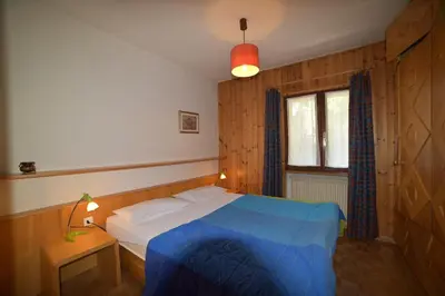 a bedroom with a blue bed and a window at Il cirmolo in Vigo di Fassa