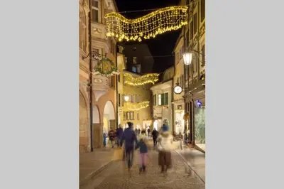 a group of people walking down a street at night at Casa Al Duomo-Nel cuore storico di Merano in Merano