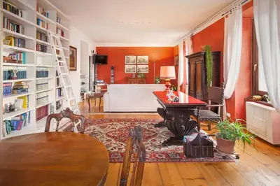 a living room with orange walls and a table and chairs at Casa Al Duomo-Nel cuore storico di Merano in Merano