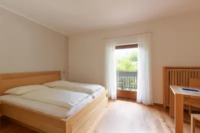 a bedroom with a bed and a window and a desk at BNB Garni Kreithof in Caldaro