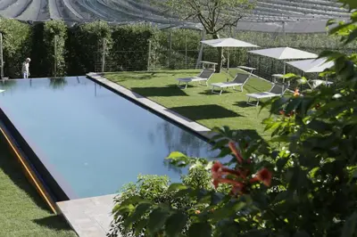 a swimming pool in a yard with chairs and umbrellas at BNB Garni Kreithof in Caldaro