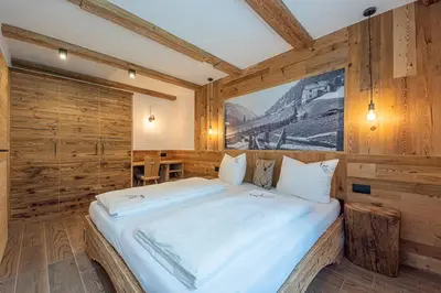 a bedroom with a large bed in a room with wooden walls at Lüch dl Jëinder in San Martino in Badia