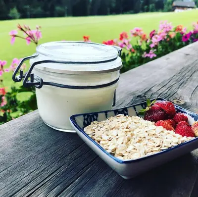 a container of milk and a bowl of granola and strawberries at Lüch dl Jëinder in San Martino in Badia