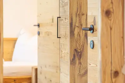 a wooden door in a bedroom with a bed at Lüch dl Jëinder in San Martino in Badia
