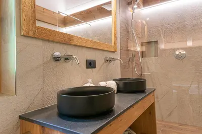 a bathroom with two black sinks on a counter at Lüch dl Jëinder in San Martino in Badia