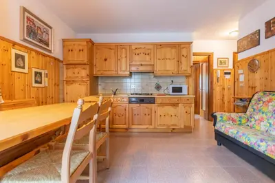 a kitchen with wooden cabinets and a wooden table at Condominio Le Coste in Falcade