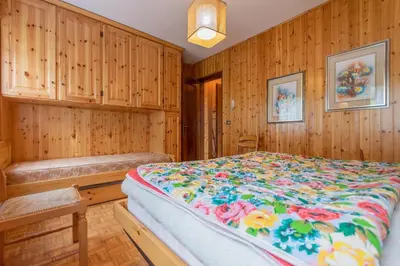 a bedroom with a bed and wooden walls at Condominio Le Coste in Falcade