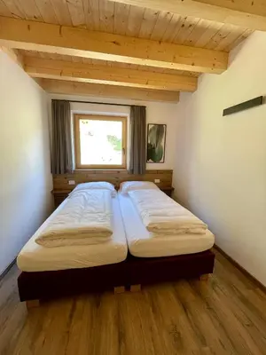 a bedroom with two beds in a room with a window at Sartu Apartments in San Vigilio Di Marebbe