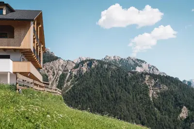 a house on a hill with mountains in the background at Sartu Apartments in San Vigilio Di Marebbe