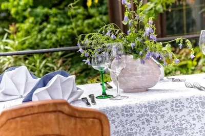 a table with wine glasses and a vase with purple flowers at Hotel Brückenwirt in Novacella