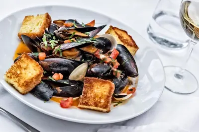 a plate of food with mussels and toast on a table at Hotel Brückenwirt in Novacella