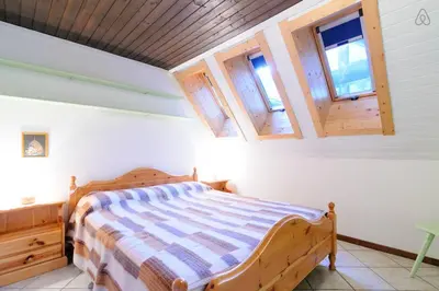 a bedroom with a wooden bed in a room with windows at Appartamento MARMOLADA - CANAZEI in Canazei