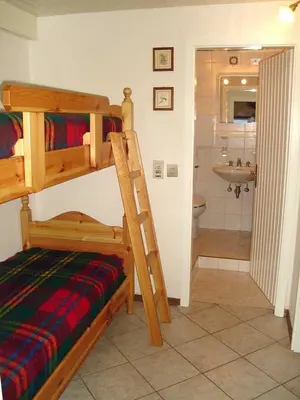 a bedroom with a bunk bed and a bathroom at Appartamento MARMOLADA - CANAZEI in Canazei