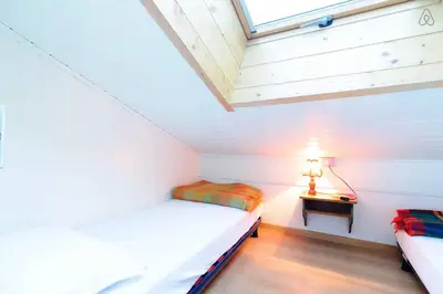 a attic bedroom with two beds and a table at Appartamento MARMOLADA - CANAZEI in Canazei
