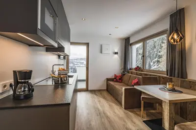 a kitchen and living room with a couch and a table at Aurela Mountain Chalets in Selva di Val Gardena