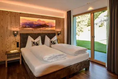 a bedroom with a large bed with a large window at Aurela Mountain Chalets in Selva di Val Gardena