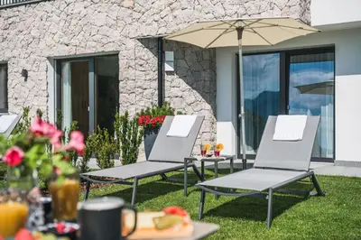 two chairs and an umbrella on a lawn at Aurela Mountain Chalets in Selva di Val Gardena