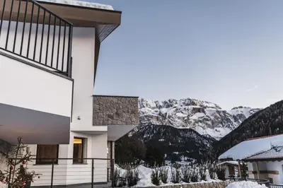 a building with snow covered mountains in the background at Aurela Mountain Chalets in Selva di Val Gardena