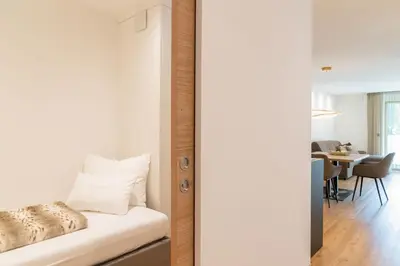 a bedroom with a bed and a dining room at Nice Living Neue- Moderne Apartments im Herzen von Brixen - kostenlose Brixencard - ideal für Familien, Paare, Geschäftsreisende und allen Urlaubs Hungrigen in Bressanone