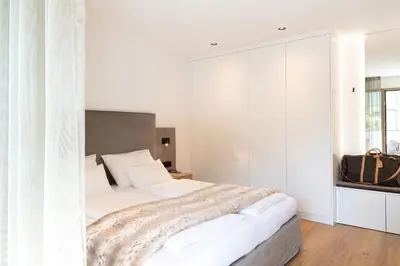 a bedroom with a large bed with white walls at Nice Living Neue- Moderne Apartments im Herzen von Brixen - kostenlose Brixencard - ideal für Familien, Paare, Geschäftsreisende und allen Urlaubs Hungrigen in Bressanone