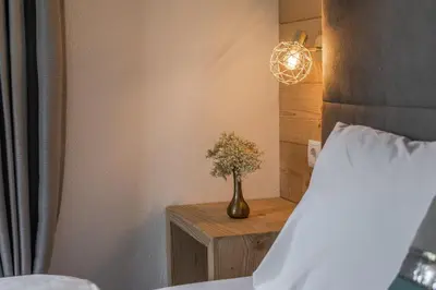 a vase of flowers on a table next to a bed at Apartment Dolomites Nest in San Martino in Badia