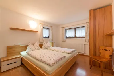 a bedroom with a bed and a table and windows at Ottohof - Feldblick in Colle Isarco