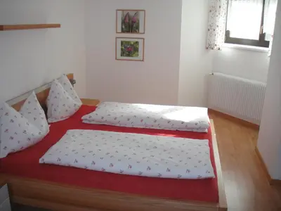 two twin beds in a room with a red mattress at Ottohof - Feldblick in Colle Isarco