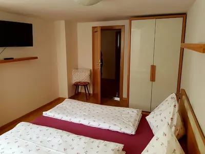 a bedroom with two beds and a tv on the wall at Ottohof - Feldblick in Colle Isarco