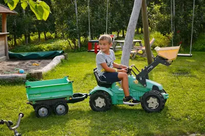 a young boy riding on a toy tractor at Schlettererhof in Tirolo