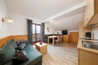 a living room with a couch and a kitchen at Schlettererhof in Tirolo