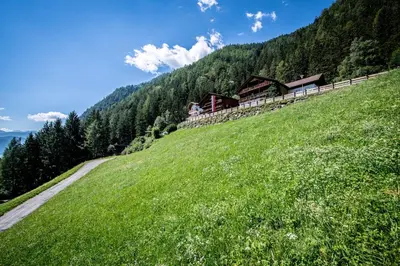 a grassy hill with a house on top of it at Gasthof Bauhof in Brunico