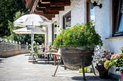 a patio with tables and chairs and an umbrella at Gasthof Bauhof in Brunico