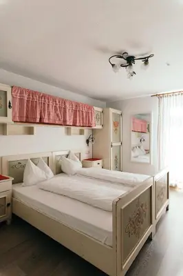 a bedroom with a large bed with white sheets at Gasthof Residence Brugghof & Erlhof in Campo Tures