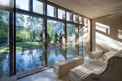 a room with large windows looking out onto a river at Adler Spa Resort Balance in Ortisei