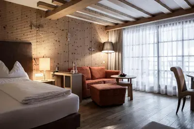a bedroom with a bed and a chair and a couch at Adler Spa Resort Balance in Ortisei