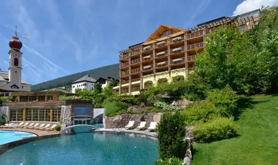 a hotel with a swimming pool in front of a building at Adler Spa Resort Balance in Ortisei