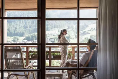 a woman standing on a balcony looking out of a window at Adler Spa Resort Balance in Ortisei