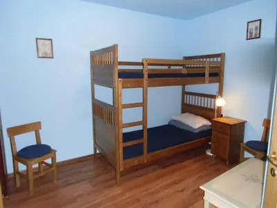a bedroom with two bunk beds and a table and chairs at Rio Gambis Apartment in Cavalese
