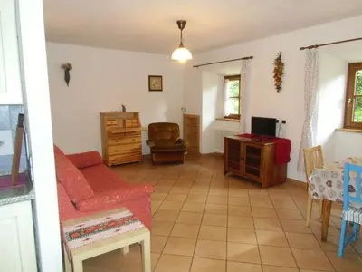 a living room with a red couch and a table at Rio Gambis Apartment in Cavalese