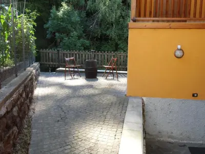 a patio with two chairs and a trash can at Rio Gambis Apartment in Cavalese