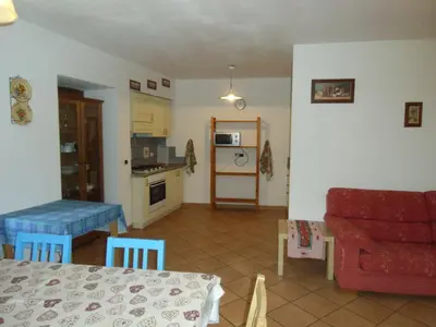 a living room with a red couch and a kitchen at Rio Gambis Apartment in Cavalese