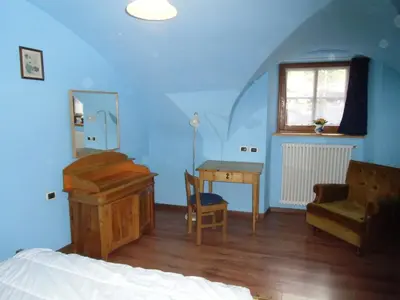 a bedroom with a bed and a desk and a window at Rio Gambis Apartment in Cavalese