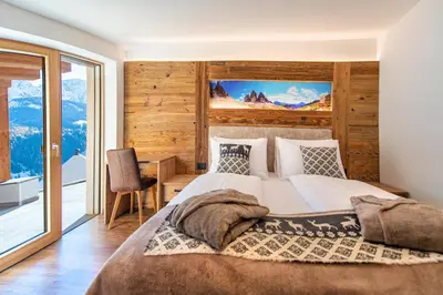 a bedroom with a bed and a desk and a window at Luech da Perteut - Panorama and Wellness in Santa Cristina in Val Gardena
