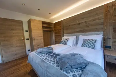 a bedroom with a large white bed with wooden walls at Luech da Perteut - Panorama and Wellness in Santa Cristina in Val Gardena